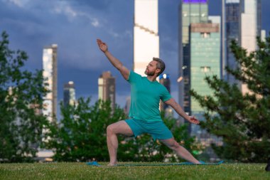 Kentsel fitness yaşam tarzı. Güç için yoga. Fitness olgun bir adam. Esnek atlet pozu. Şehirde fitness eğitimi. Spor salonu rutini. Dengeli vücut kontrolü. Yoga sınıfındaki son sınıf öğrencileri eşit poz veriyor.