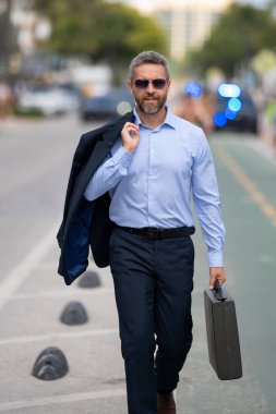 İş adamı işe yürüyerek gider. Hispanik iş adamı sokakta güven içinde yürüyor. Ofis çalışanı ofise gidiyor. Olgun bir iş adamı şehirde yürüyor. Dışarıda yürüyen bir iş adamı. İş biçimi