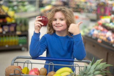 Bakkal arabasında taze meyve ve sebze. Marketteki sağlıklı gıda seçimi. Çocuk markette meyve seçiyor. Çocuk süpermarketten taze yiyecek alıyor. Çocuklarla market alışverişi.