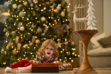 Noel ağacının yanında kış pijaması içinde mutlu bir çocuk. Noel ve Yeni Yıl kavramı