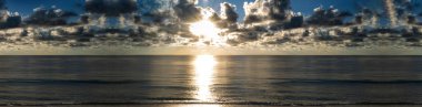 Okyanus ufkunda gün doğumu panoramik. Deniz bayrağının üzerinde şafak vakti. Gün batımlı güzel bir deniz manzarası. Sakin suyun üzerinde sabah güneşi. Huzurlu gündoğumu okyanus manzarası. Manzaralı okyanus gündoğumu. Bulutlu deniz manzarası