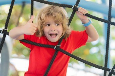 Küçük çocuk oyun alanında oynuyor. Mutluluk duygusu, eğlence, neşe. Bir çocuğun gülümsemesi.