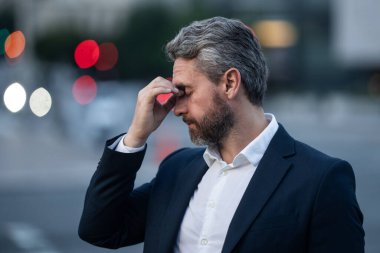 Baş ağrısı çeken yorgun bir adam. Başa dokunmak, ağrıyı dindirmek, migren. İş sorunları. İflas, mali sorun ve kriz konsepti. Bin yıllık İspanyol adamın başı ağrıyor. Migren.