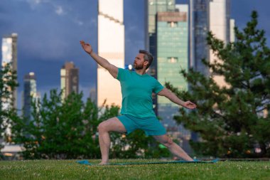 Şehir sporları yaşam tarzı. Yaşlı yetişkinler için yoga. Olgun bir sporcu. Şehirde spor eğitimi. Spor salonunda spor rutini. Yoga sınıfındaki son sınıf öğrencileri parkta poz veriyor. Şehirde spor