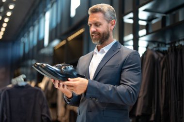Moda mağazasındaki müşteri farklı ayakkabı stillerini değerlendirir. İş adamı kendine güvenerek şık ayakkabıları bir ayakkabı mağazasında seçer. Resmi görünmek için klasik deri ayakkabılar. Resmi ayakkabılar. Deri ayakkabılar.