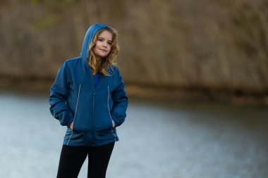 Nehrin kıyısındaki iskelede bir çocuk. Çocuk nehir kıyısında kayalıklarda yürüyor. Çocuk açık havada düşünceli. Doğada sıradan bir genç. Nehir kenarında sakin ve sakin bir zaman. Sonbahar parkında temiz hava alan çocuk.