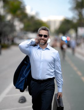 İş adamı şehirde güvenle yürüyor. Sokakta yürüyen bir iş adamı. Ofise doğru yürüyen yakışıklı bir iş adamı. Kendine güvenen girişimci iş adamı dışarıda yürüyor.