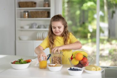Çocuk evde sağlıklı kahvaltı yapıyor. Çocuk yemek masasında taze meyve yiyor. Mutfakta lezzetli yemekler yiyen mutlu bir çocuk. Aile yemeği sırasında çocuk. Küçük çocuk yemeğini ye.