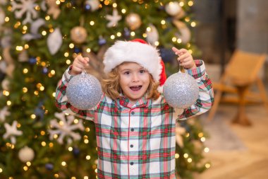 Noel Baba şapkalı çocuk evde Noel ağacının yanında. Neşe ve mutluluk. Çocukluk anları