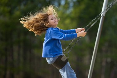 Salıncaktaki çocuk. Çocuk bahçesinde mutlu bir çocuk. Kaygısız çocuk dışarıda sallanıyor. Mutlu çocuklar dışarıda oynuyor. Sarışın çocuk mutluluktan uçuyor. Dışarıdaki oyuncu çocuk. Çocuk suratı. Mutlulukla sallanan çocuk