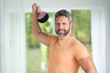 Orta yaşlı adam evde kettlebell kaldırıyor. Latin Adam Ağırlıkla Egzersiz Yapıyor. Kettlebell Kapalı Salon 'da Olgun Adam. 40 'lı yaşların adamı, çaydanlık kaldırıyor. Sabah egzersizleri. Kettlebell ile Çalışma