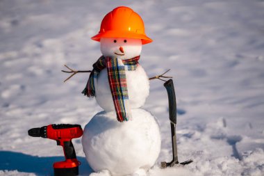 Elinde testere ve çekiç tutan kardan adam. Kardan adam marangoz. Kış donanım mağazası tasarımları için kardan adam üreticisi. Kışın kardan adam inşaatı
