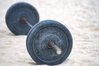 Halter spor ekipmanları. Spor geçmişi. Yaz sporu için kumda halter. Kum arka planda halter. Spor salonunda halterle idman yapıyorum. Spor afişi