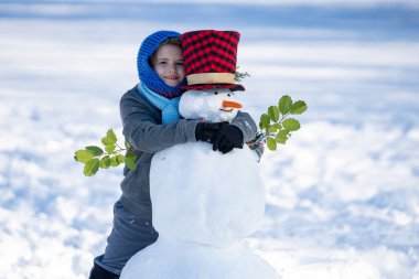 Çocuk karlı günün tadını çıkarıyor. Taze kardan hoşlanan çocuk. Kış çocuğunun yakın plan yüzü. Noel kartı için sevimli bir çocuk. Kar atan çocuk. Kış çocuğu suratı. Çocuk kış aktivitesi