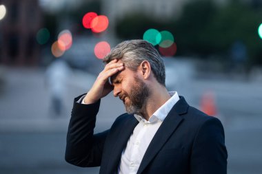 Dışarıda baş ağrısı çeken yorgun bir iş adamı. Migren ağrısını dindiren bir adam. Finansal sorunlar ve stres. İş krizi ve iflas kavramı. İş adamı endişeli ve stresli