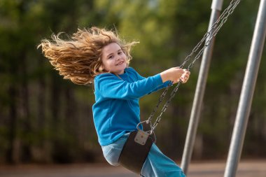 Heyecanlı çocuk eğleniyor. Çocuk bahçesinde mutlu bir çocuk. Havada sallanan kaygısız çocuk. Mutlu çocuklar dışarıda oynuyor. Sarışın çocuk heyecandan titriyor. Dışarıdaki oyuncu çocuk. Komik çocuk suratı