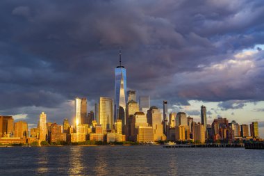Karanlık gökyüzü olan New York. Dramatik bulutlarla New York şehrinin silueti. New York şehrinin altın gecesinde Manhattan gökdelenleri. New York 'ta Manhattan' ın ikonik şehir manzarası. New York Panoraması