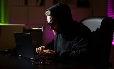 Şifreli para hackleme. Şifreli para için hackleme. Kripto para birimi hack konsepti. Kapüşonlu, karanlık gece temalı bir bilgisayar korsanı. Dijital veri güvenliği kavramı. Hackerlar saldırır. İnternet siber suçları