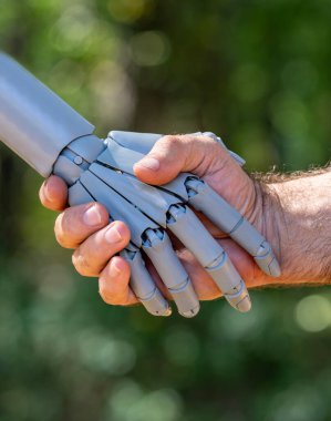 Robot ve insan eli. Robot ve erkek tokalaşması yeşil doğada. Ai ve insan elleri tokalaşıyor. Robot eller insan eliyle etkileşime giriyor. İnsanlarla robot eli