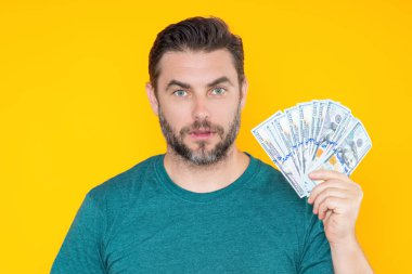 Paralı bir adam. Dolar banknotları. Elinde bir deste para tutan adamın portresi. Dolar, kredi, internet bankacılığı. Dolar banknotlarını, banka kredisini, mali tasarrufları gösteren zengin bir adam.