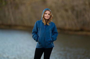 Nehrin kıyısındaki iskelede bir çocuk. Çocuk açık havada düşünceli. Doğada sıradan bir genç. Nehir kenarında sakin ve sakin bir zaman. Huzurlu bir çocukluk. Sonbahar parkında temiz hava alan çocuk.