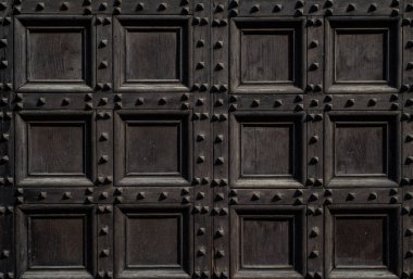 Antika ahşap kapı deseni. Geometrik desenli klasik kahverengi kapı. Eski ahşap mimari ve dekoratif yüzey. Eski bina kapısında kare desenli paneller. Eski tasarım