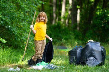 Çocuk çöp toplamaya yardım ediyor. Kirli orman. Çöp yığını. Gezegen kirliliği çevre koruma kavramı. Ormanı temizliyorum. Çöp torbalarına çöp koyan çocuk, çevre koruması