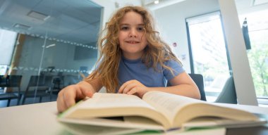 Komik çocuk kitabı okuyor. Öğrenci çocuk ders çalışıyor ve okuyor. Akıllı çocuk kitap okur. Kitaptan küçük bir öğrenci öğreniyor. Çocuk kütüphanede kitap okuyor. Eğitim ve Öğrenim. Okuma yoluyla bilgi