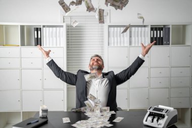 İş adamı heyecanla dolarları havaya fırlatıyor. Başarılı bir adam para saçıyor. Dolar atan zengin bir iş adamı. Para saçan yakışıklı adam.