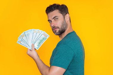 Paralı bir adam. Dolar banknotları. Elinde bir deste para tutan adamın portresi. Dolar, kredi, internet bankacılığı. Dolar banknotlarını, banka kredisini, mali tasarrufları gösteren zengin bir adam.