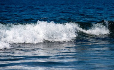 Parlayan deniz dalgaları gün ışığında parıldıyor. Okyanus dalgası yükseliyor. Parlak deniz dalgaları arka planı. Mavi yeşil deniz dalgaları desenleri. Doğanın deniz dalgaları