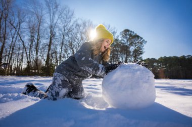 İyi kışlar. Çocuk kartopuyla oynuyor. Mavi gökyüzünün altında taze karda oynayan bir çocuk. Neşeli çocuk doğada güneşli kış gününün tadını çıkarıyor. Kardan adam yapan çocuk. Çocuk dışarıda karda oynuyor.
