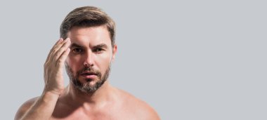 Yüzünde krema olan çekici bir adamın yakın plan portresi. Güzel adam beyaz arka planda yakın plan portresi. Çıplak omuzlar, cilt bakımı, sağlık, cilt için kozmetik. Başlık için pankart, kopyalama alanı