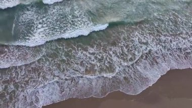 Okyanus suyu hareket halinde. Deniz dalgaları kuma yayılıyor. Güçlü dalgalar yükseliyor. Su dalgaları kıyıya yaklaşıyor.