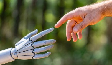 Robot el insanlarla temas kuruyor. Robot yeşil doğa arka planında insan eline dokunuyor. Ai ile insan eli bağlantısı. Robot eller insan eliyle etkileşime giriyor.