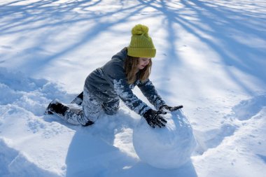 Güneşli bir kış gününde kardan adam yapan gülümseyen bir çocuk. Dışarıda karda oynayan mutlu kız. Sevimli çocuk kardan adam yapıyor. Çocuk nükteli kar tanesi. Çocuk kış tarlasında büyük bir kar topu inşa ediyor.