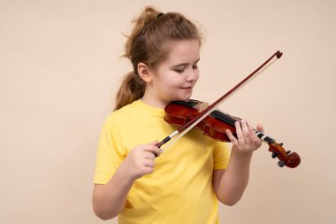 Keman çalan çocuk melodi çalışıyor. Çocuk kemanla izole edilmiş stüdyo arkaplanı çalıyor. Çocuk müzik öğreniyor. Kemanı olan çocuk sesten hoşlanıyor. Çocuklar için klasik müzik. Keman çocuk dersi