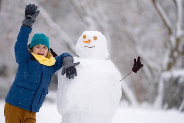 Mutlu Çocuk kışın kardan adam için kartopu yapıyor. Çocuk karda oynuyor. Açık havada aktif kış oyunları. Çocuk karla oynarken eğleniyor. Çocuklar için açık havada kış tatili. Güneşli kış gününde çocuk oyunu