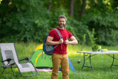 Adam doğada kamp yapmayı seviyor. Kamp gezisi. Yürüyüşten sonra bir çadırda dinleniyor. Huzurlu bir kamp alanında tatil. Yazın piknik. Açık hava macerasının özgürlüğü. Erkek kampı ve rahatlama