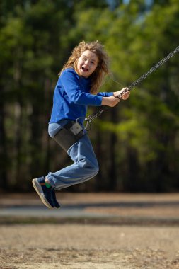 Heyecanlı çocuk eğleniyor. Çocuk bahçesinde mutlu bir çocuk. Havada sallanan kaygısız çocuk. Mutlu çocuklar dışarıda oynuyor. Sarışın çocuk heyecandan titriyor. Dışarıdaki oyuncu çocuk. Komik çocuk suratı