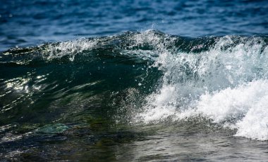 Deniz dalgaları arka planı. Köpüklü dalga hareketi. Deniz dalgaları turkuaz tonlarla yükselir. Dalgalar tropikal okyanus suyunda kırılır. Dalga su dokusu