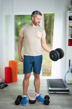 Orta yaşlı adam dambılları kaldırıyor. Latin Adam Ağırlıkla Egzersiz Yapıyor. Salonda Dambıllı Olgun Adam. Spor adamı Dambılları kaldırıyor. Sabah egzersizleri. Dambıllarla antrenman