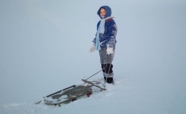 Çocuk karda oynuyor. Çocuklar için hareketli bir kış günü. Kışın çocukluk. Kardan çocuk temasında çocuk kayıyor. Noel ve çocuklu yeni yıl sahnesi. Kızaklı çocuk karda oynuyor