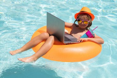 Konseptin dışında çalış. Çocuk yüzme havuzunda dizüstü bilgisayarla çalışıyor. Yaz işleri.