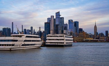 Şehir manzarasına gökdelenler hükmediyor. Tekneler New York rıhtımı boyunca dinlenir. Kentsel nehir manzarası Manhattan 'ı tanımlar. New York şehri alacakaranlıkta yükseliyor. Yatlar kıyıya yakın yüzer. NYC seyahat simgesi