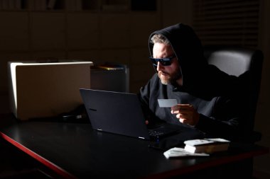 Kişisel bilgi güvenliği hackleniyor. Şifreli veri hackleme. Şifreli para için hackleme. Kripto para birimi hack konsepti. Kapüşonlu, karanlık gece temalı bir bilgisayar korsanı. Korsanlar saldırıyor