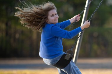 Dışarıda sallanan mutlu çocuk. Salıncakta gülen çocuk. Oyun bahçesinde oynayan neşeli çocuk. Heyecanlı çocuk salıncakta sallanıyor. Yaz parkındaki sevimli çocuk. Parkta sallanan oyuncu çocuk. Mutlu çocukluk