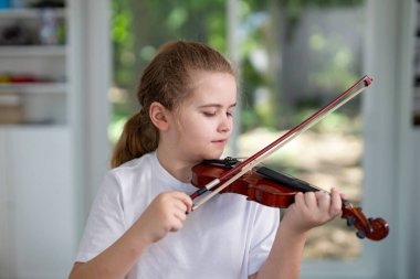 Çocuk evde keman çalıyor. Çocuk evde klasik müzik uyguluyor. Genç kemancı. Müzik aleti olan bir çocuk. Genç müzisyen keman ile müzik öğreniyor. Çocuk evde akustik keman çalışıyor.