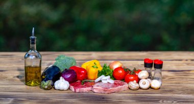 Tahta üzerinde çiğ biftek ve malzemeler. Pişirmek için taze kesilmiş et. Sarımsak ve soğanlı çiğ biftek. Taze et ızgara ya da barbekü için hazır.