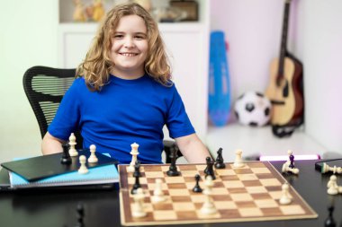 Çocuk şah mat yapıyor. Çocuk çocuk odasında satranç oynuyor